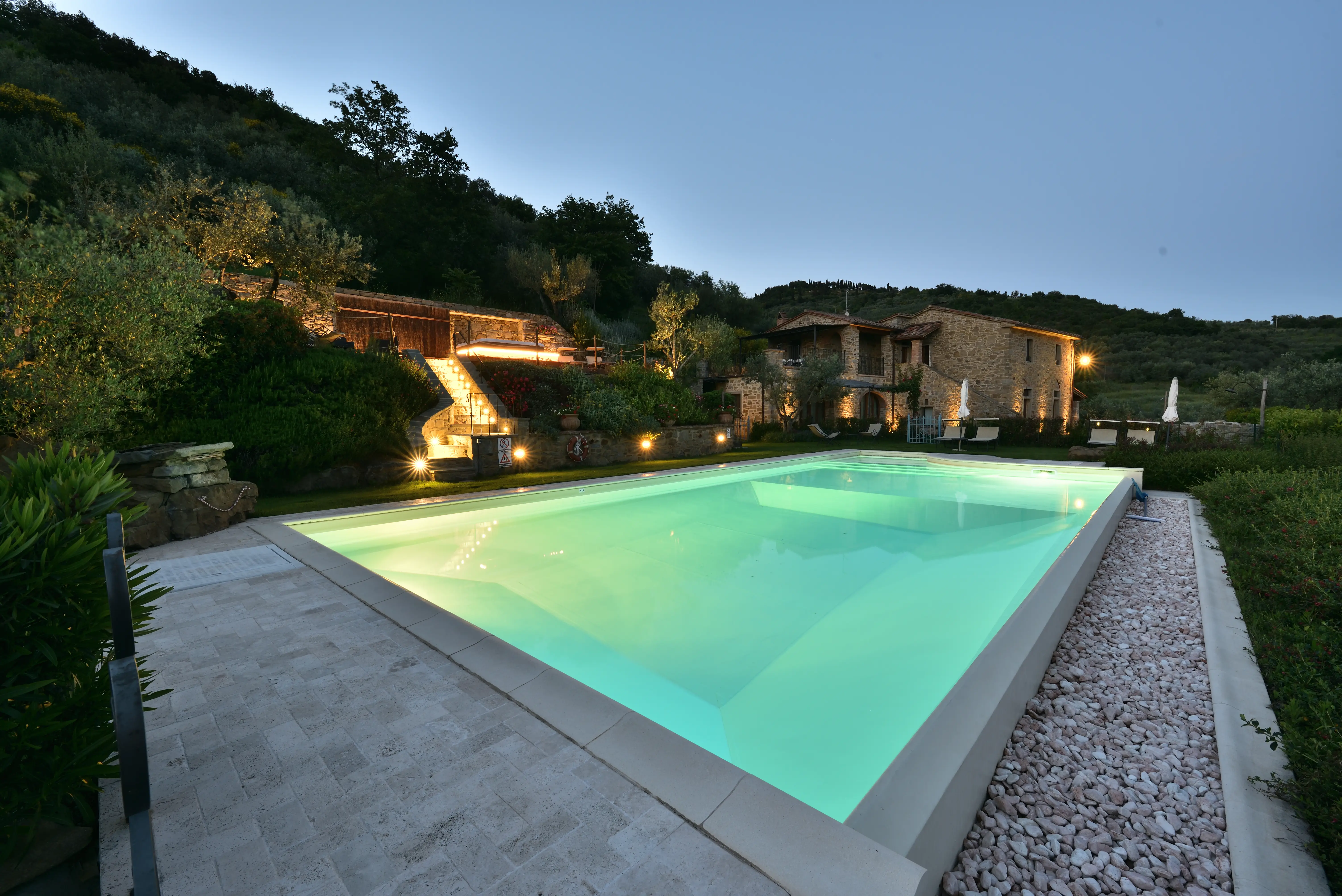 La piscina illuminata di notte davanti al casale